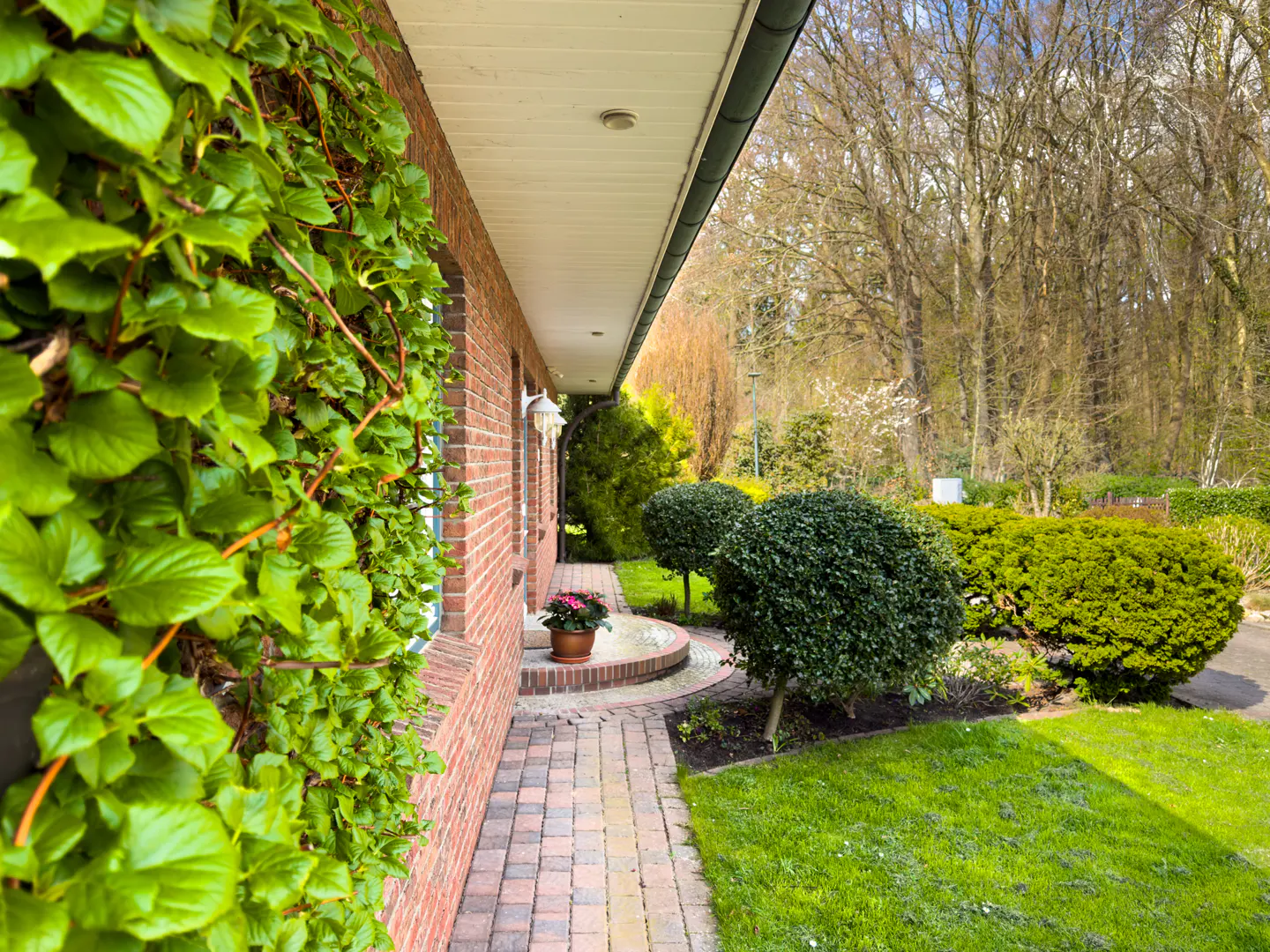 Brick house exterior with green ivy, a brick walkway, and manicured landscaping.