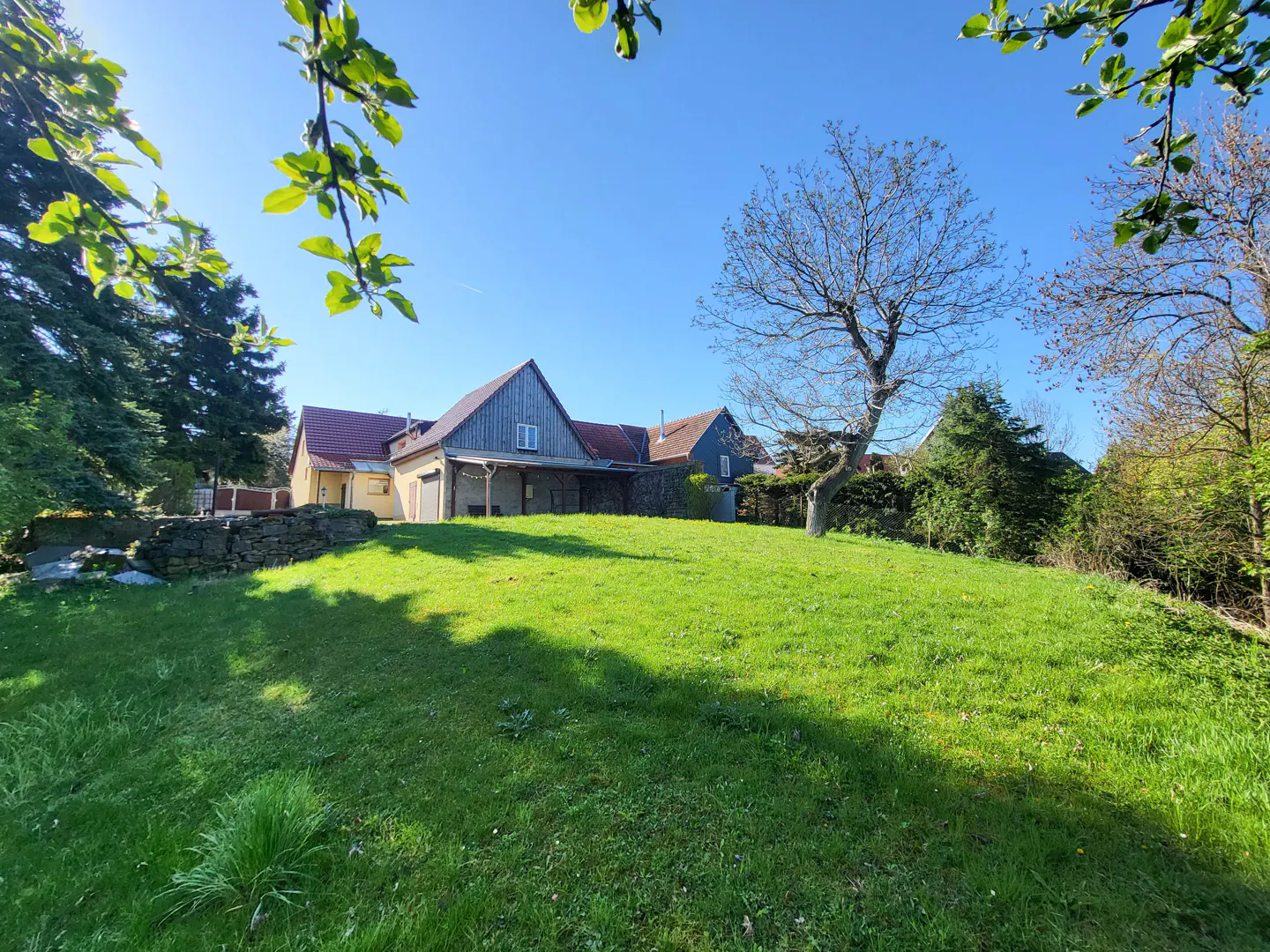 Exterior view of a house with a large green lawn on a sunny day.