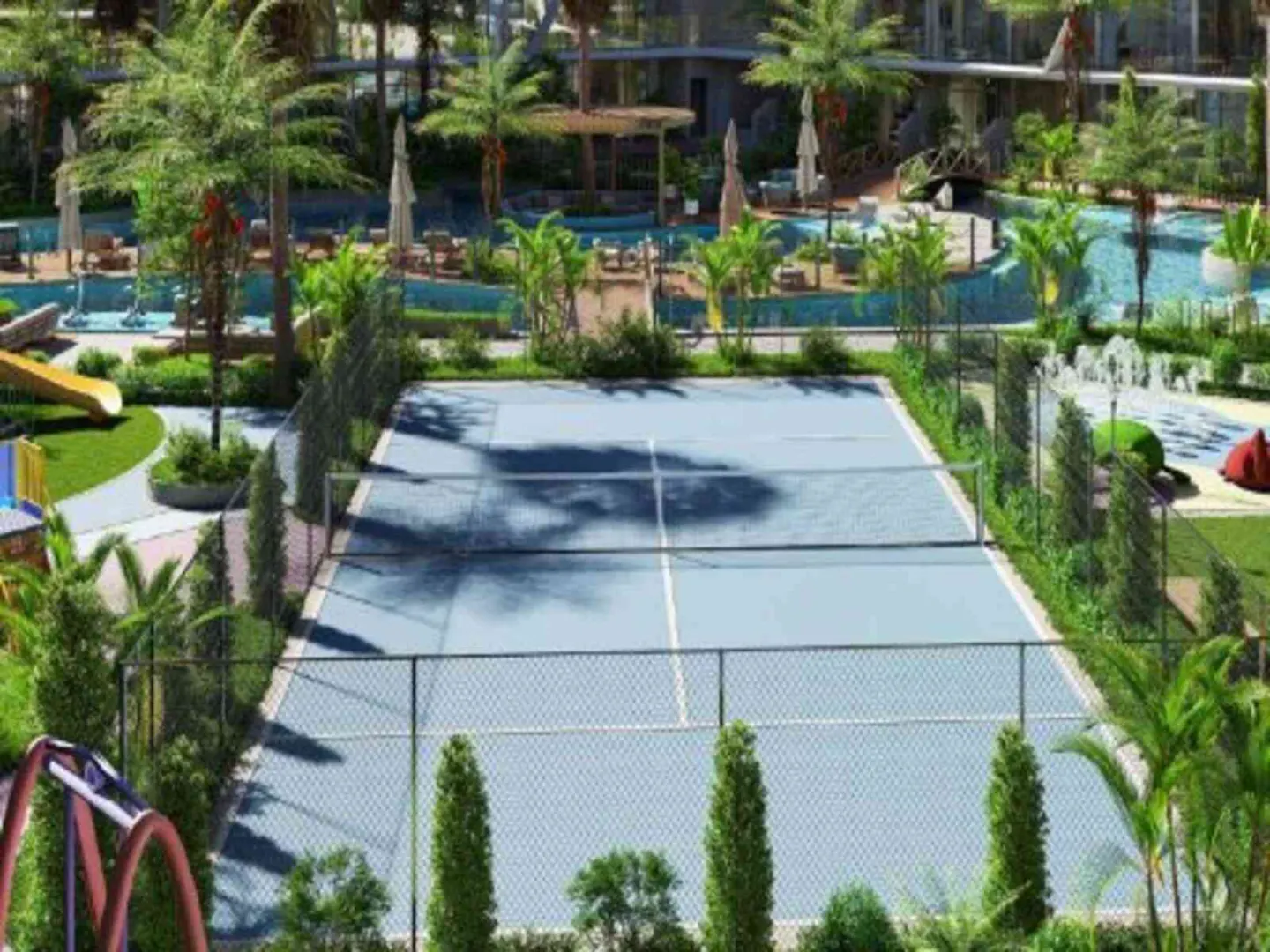 Outdoor blue tennis court surrounded by a black fence, green trees, and a resort-style pool in the background.
