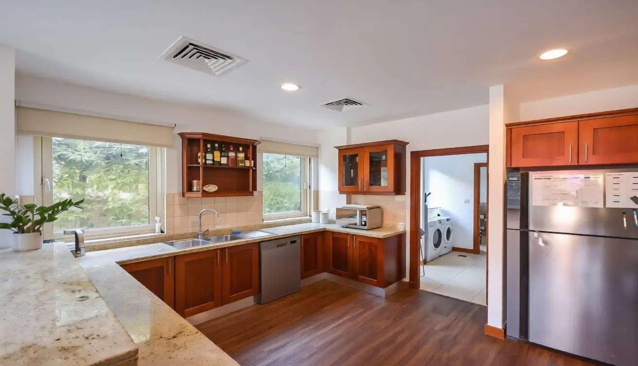 Kitchen with wood cabinets, granite countertops, stainless steel appliances, and a view into a laundry room.