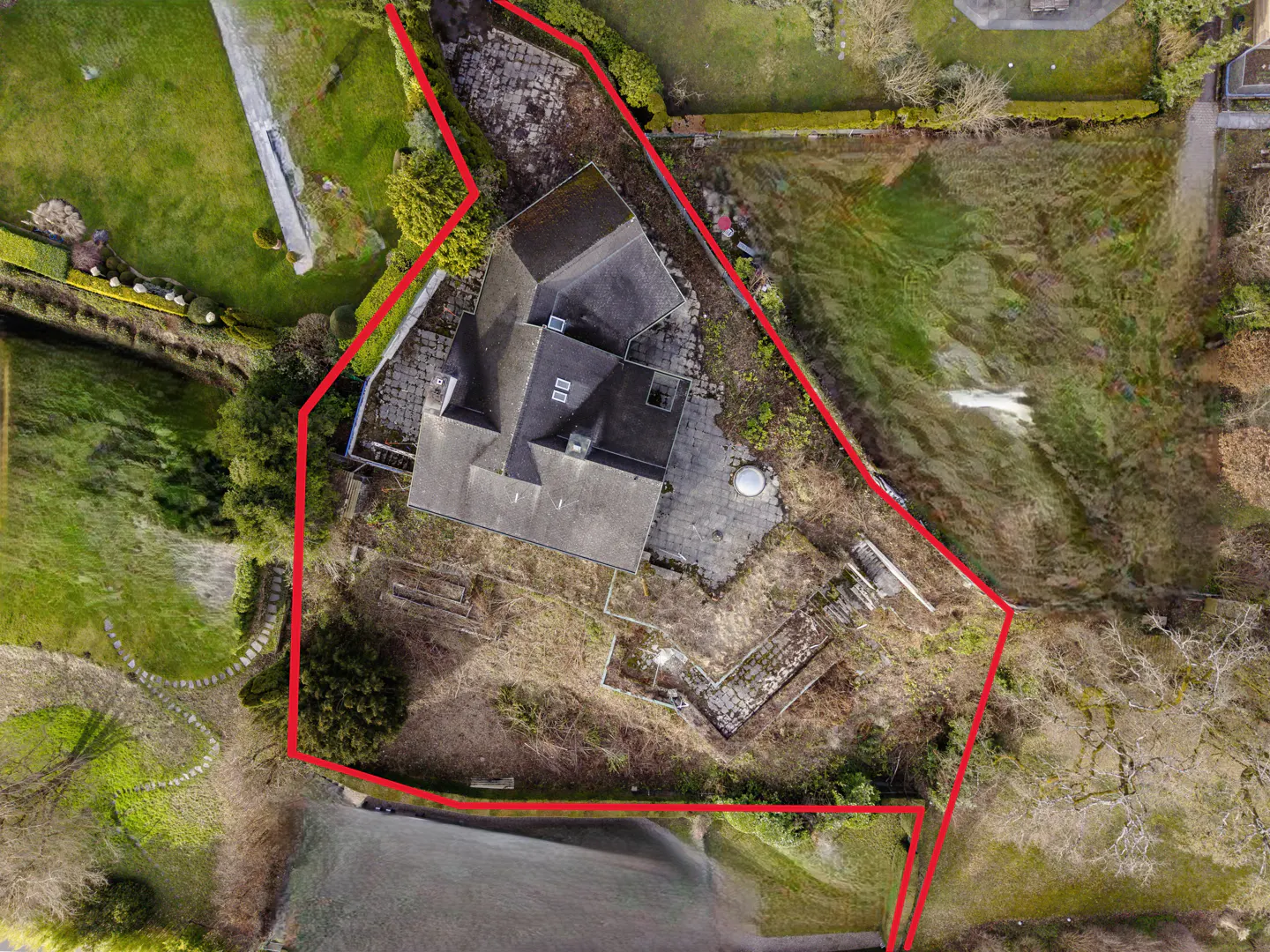 Aerial view of a house with a gray roof, surrounded by a red boundary line, and green grass.