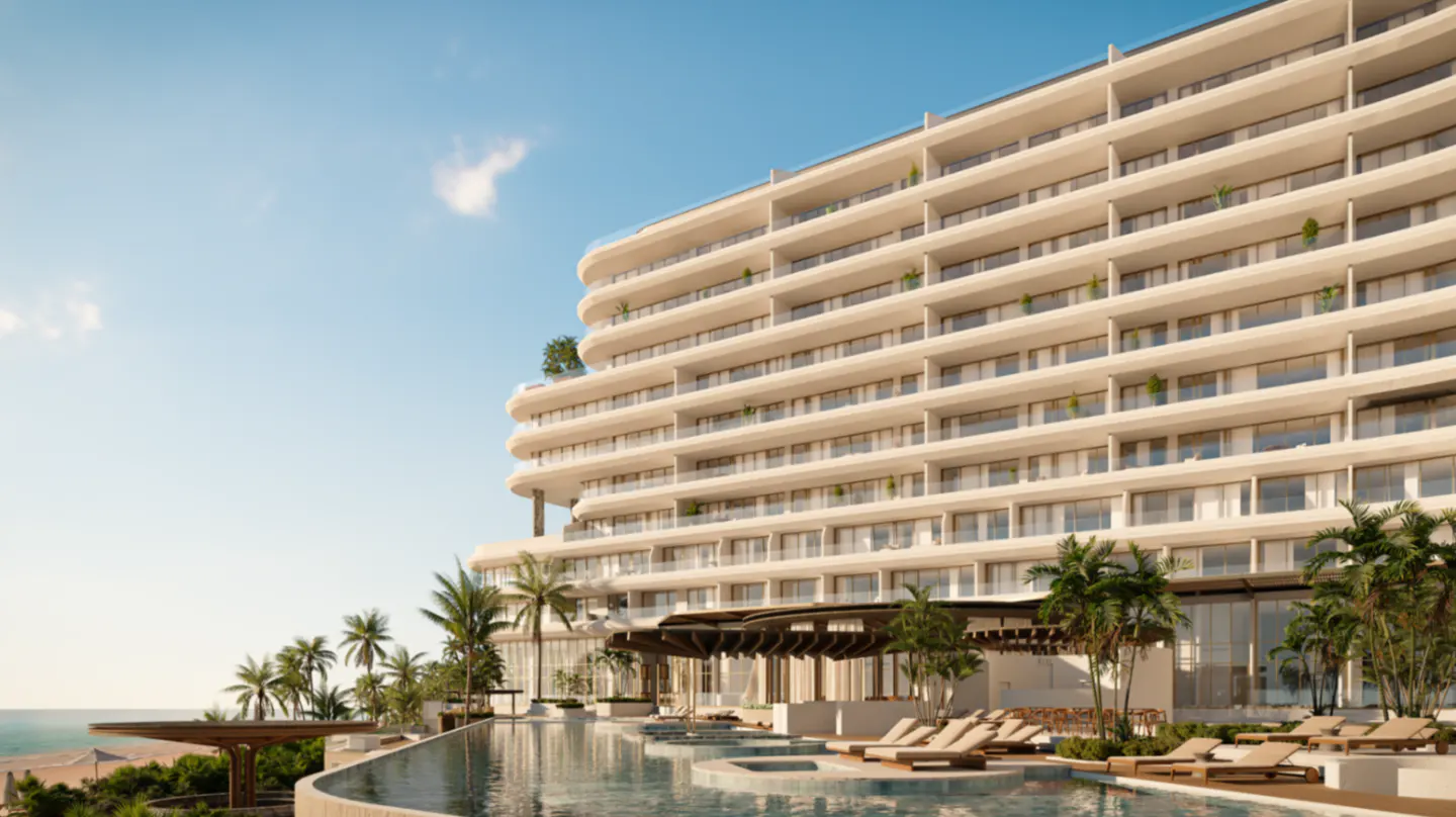 Luxury beachfront condo building with a pool, lounge chairs, and palm trees under a blue sky.