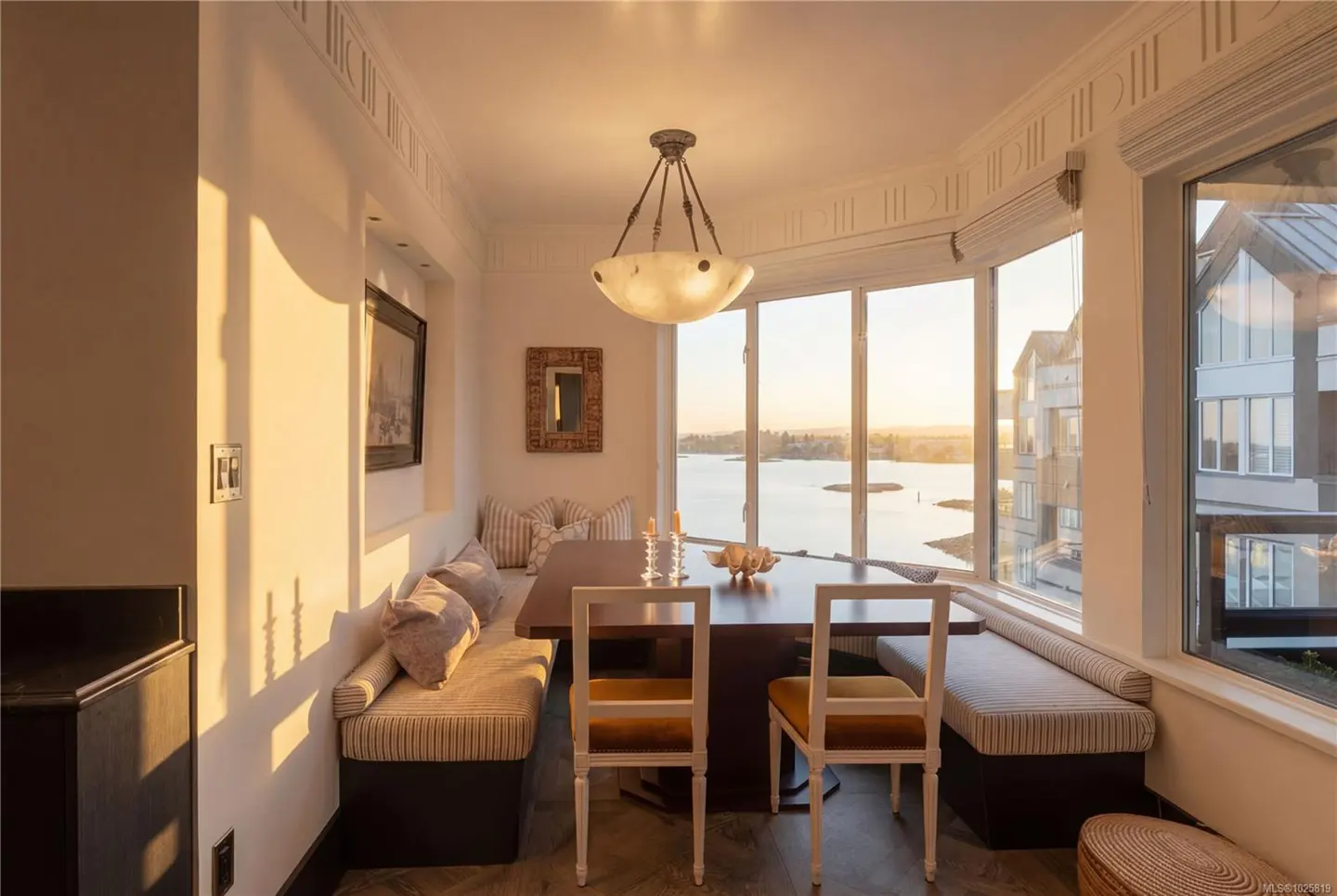 A dining area with built-in seating and a view of the water. The table is set with candles and a decorative bowl.