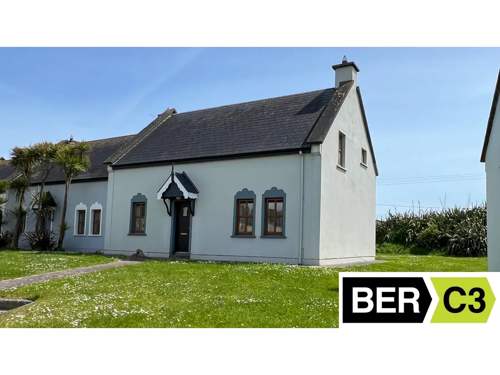 Exterior of a light blue cottage with a dark roof, black door, and green lawn. BER C3 energy rating logo in the corner.