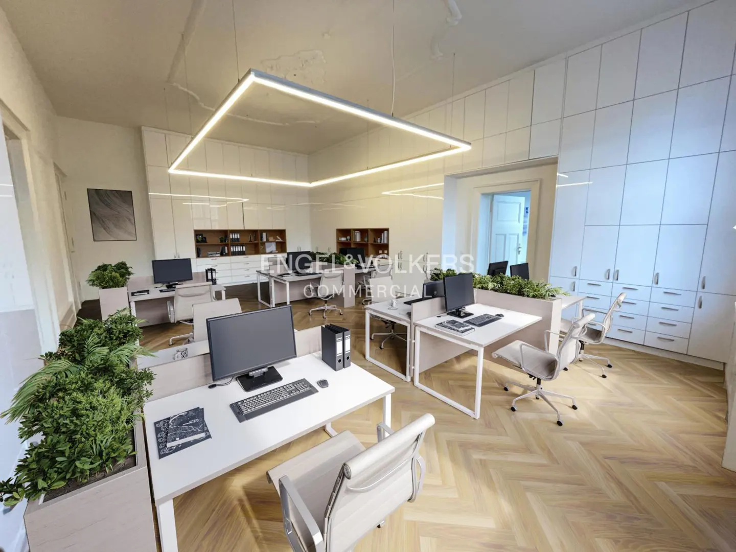 Bright office space with white desks, computers, and chairs. Herringbone wood floors and square LED lighting. Engel & Völkers logo visible.