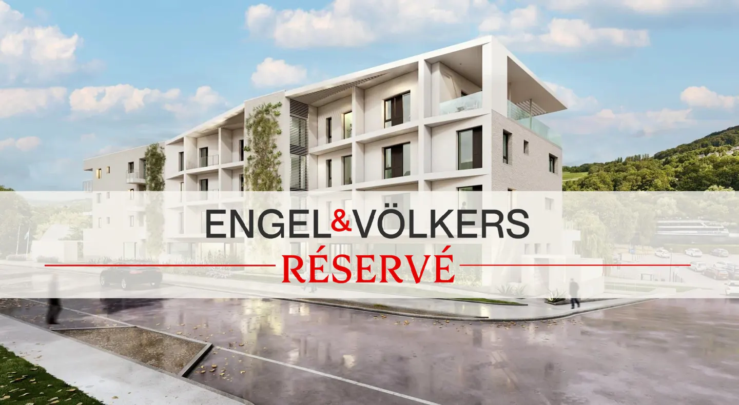Modern white building with Engel & Völkers logo and "Réservé" text overlay. Trees and blue sky in background.