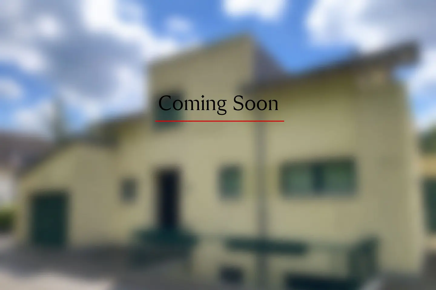 Blurred image of a yellow two-story house with "Coming Soon" text overlayed in black with a red underline.