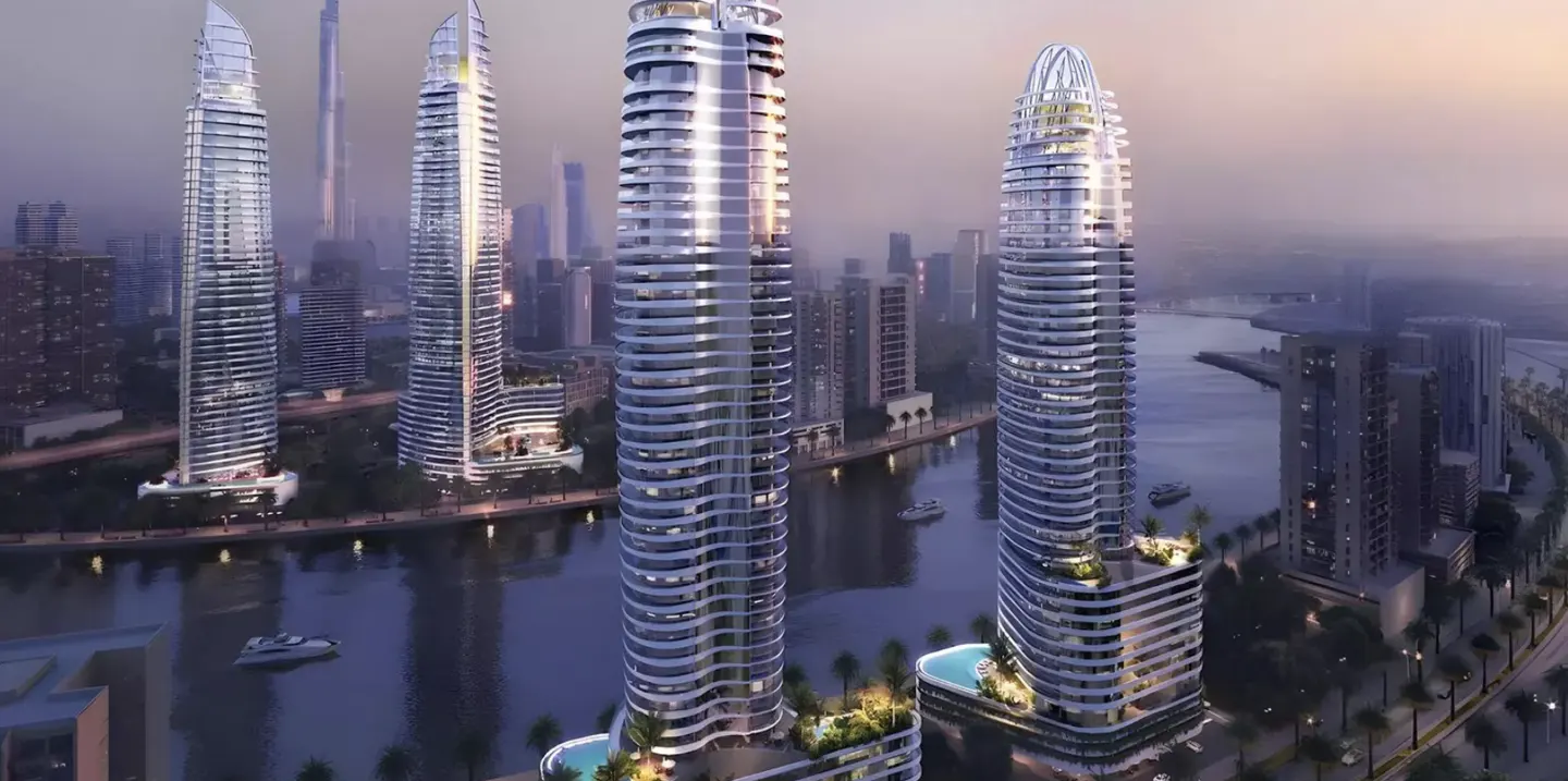 Modern high-rise condo buildings line a river in a city. The buildings are white with curved balconies. Boats are on the water.