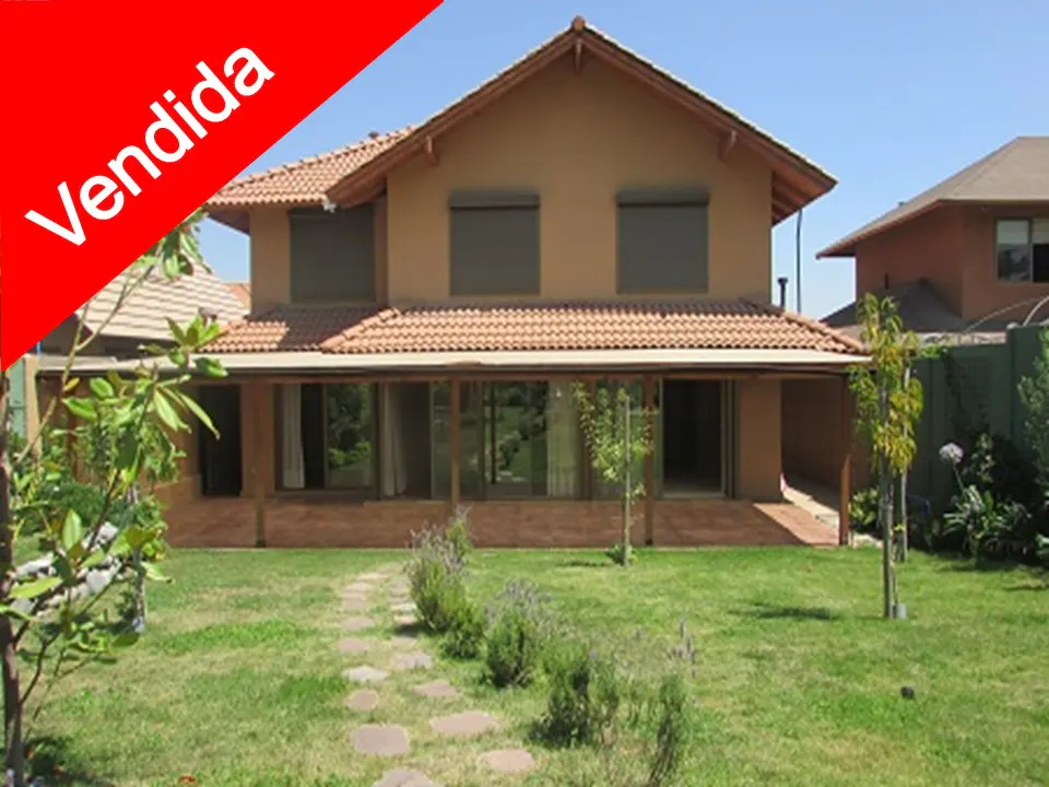 Two-story house with a red "Vendida" banner, a tile roof, and a green lawn.
