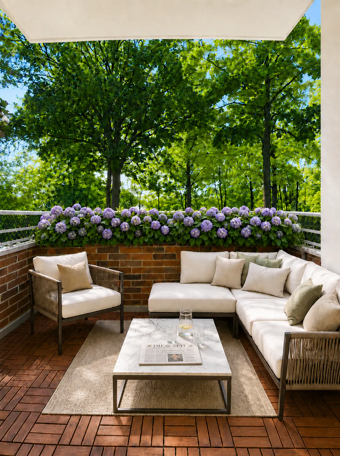 Covered patio with white sectional sofa, armchair, marble coffee table, and purple hydrangeas against a lush green forest.