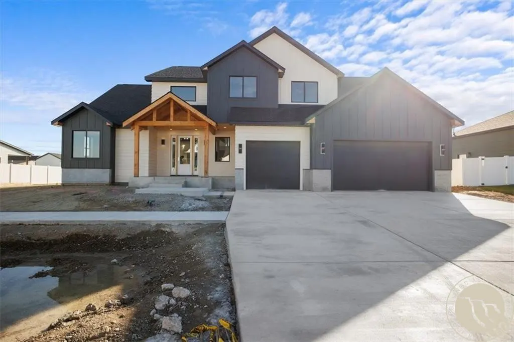 Two-story house with gray and white siding, black roof, and a two-car garage. A concrete driveway leads to the house.