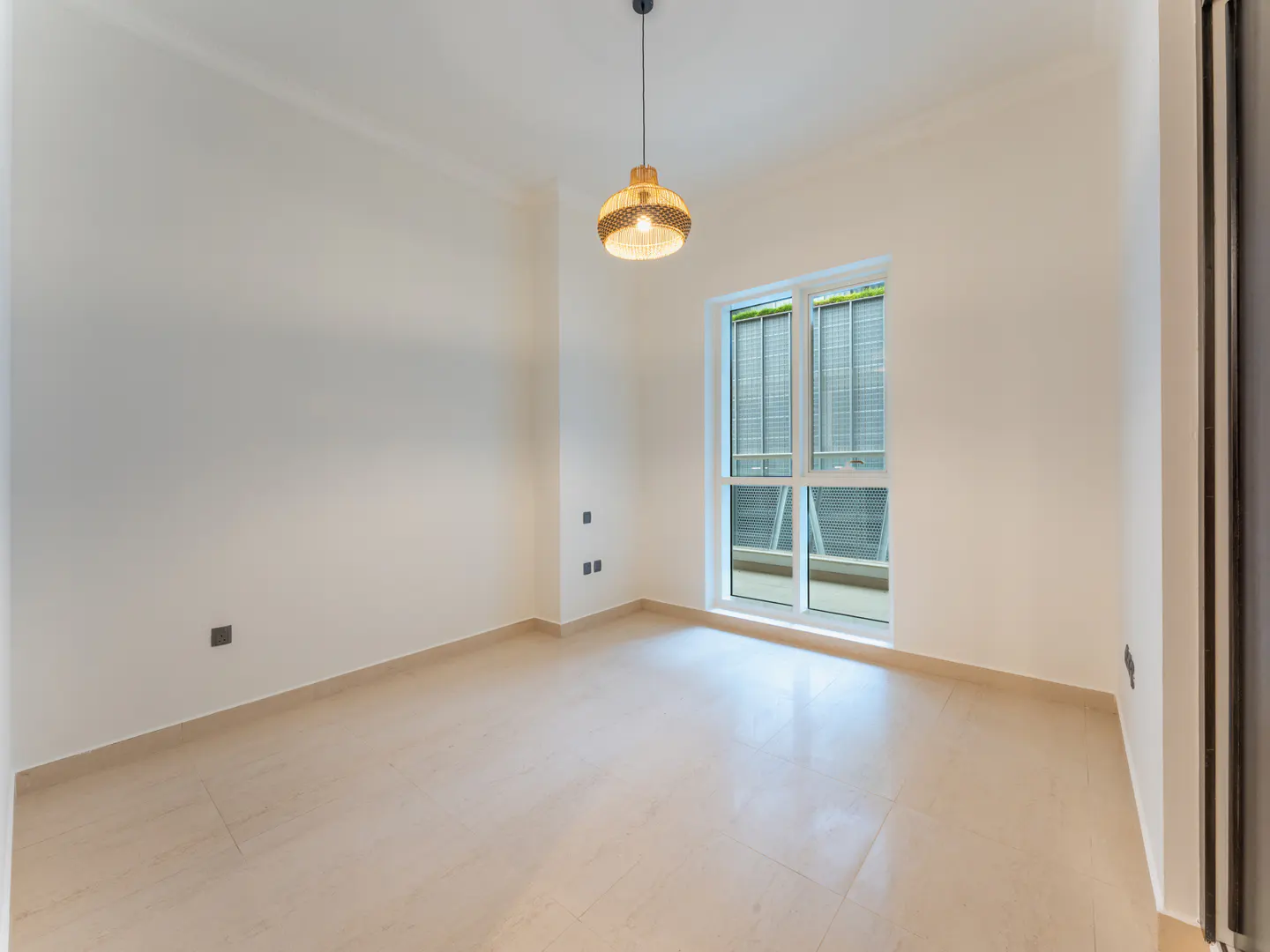 Bright, empty room with beige tile floor, white walls, and a window with blinds. A woven pendant light hangs from the ceiling.