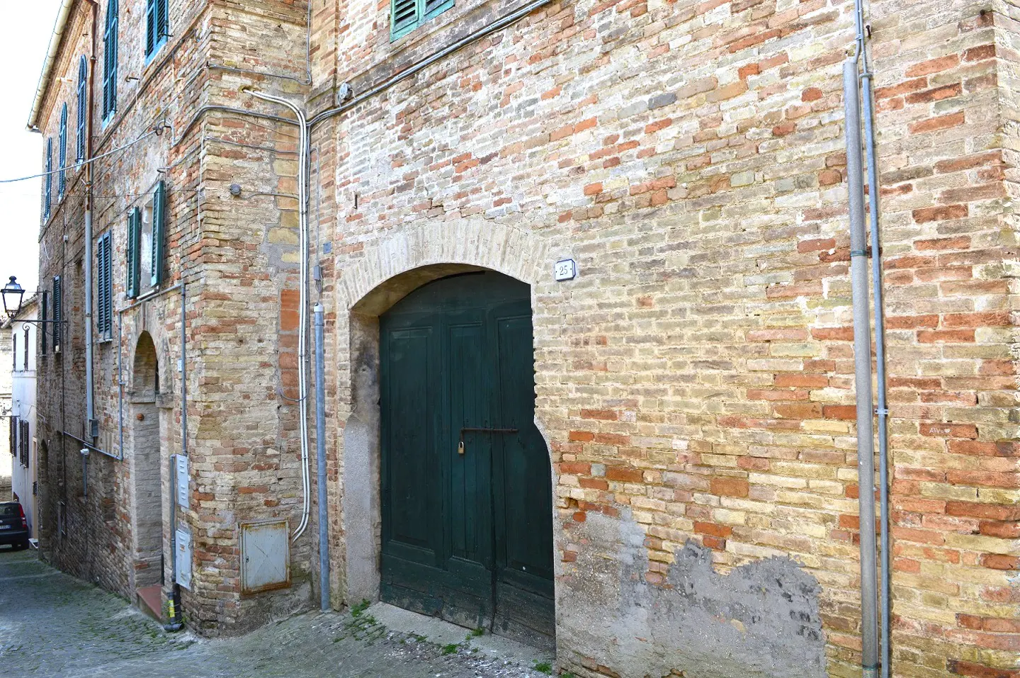 Exterior view of a brick building with a dark green door and window shutters.
