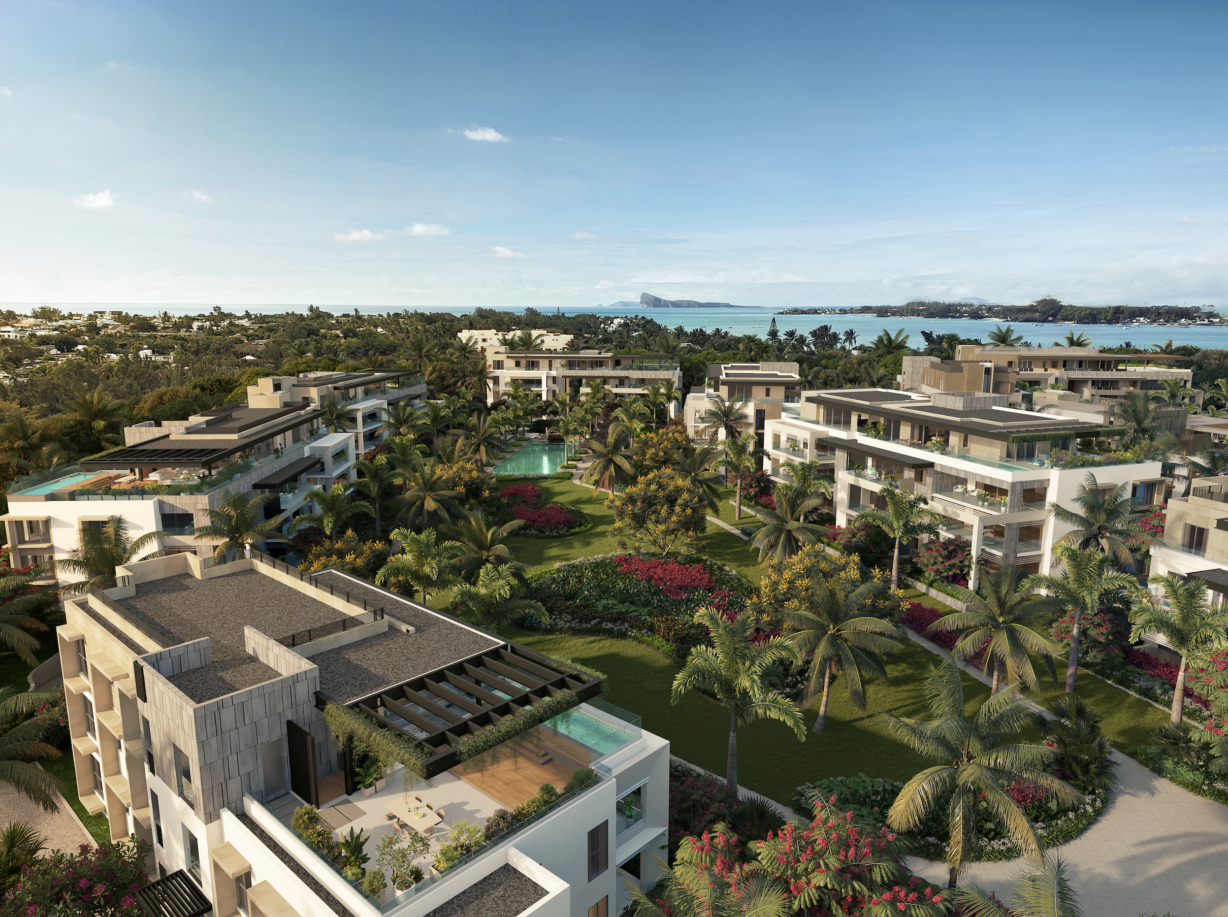 Aerial view of a modern luxury apartment complex with lush tropical gardens, swimming pools, and ocean views.