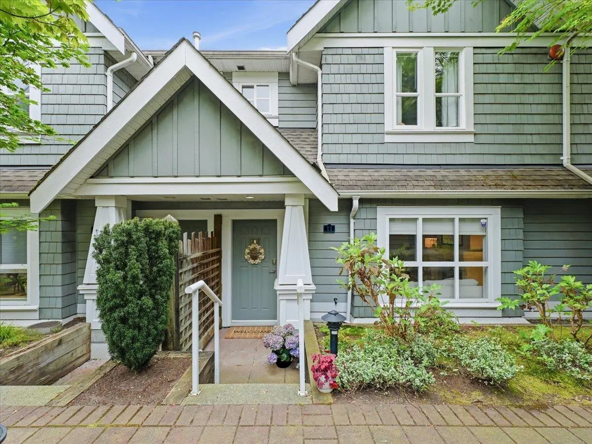 Exterior of a two-story townhouse with gray siding, white trim, and a light blue front door with a wreath.