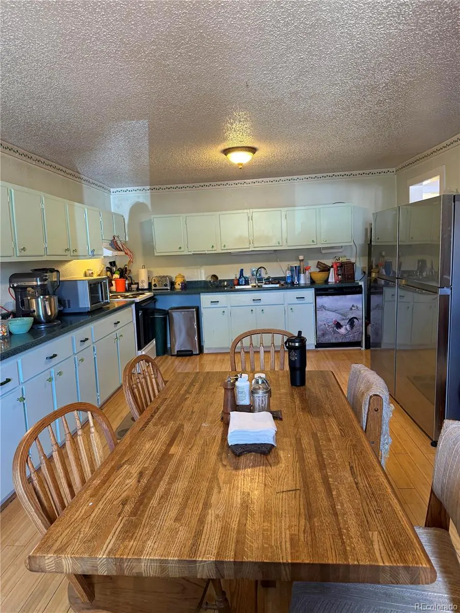 A kitchen with light blue cabinets, stainless steel appliances, and a large wooden table with chairs.