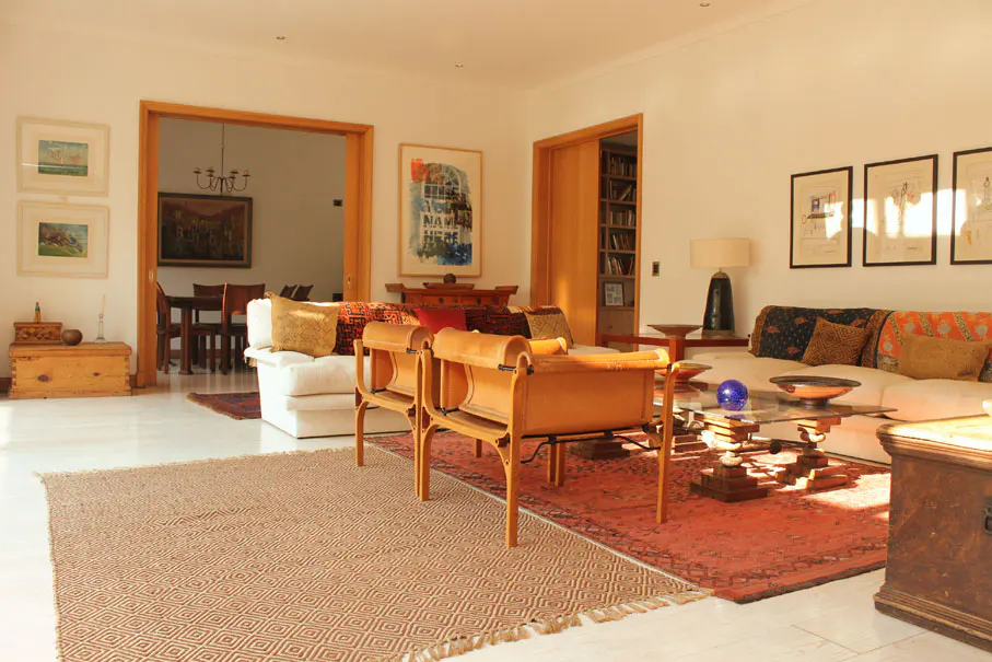 Bright living room with white walls, light wood trim, and a mix of modern and vintage furniture. A brown patterned rug covers the floor.