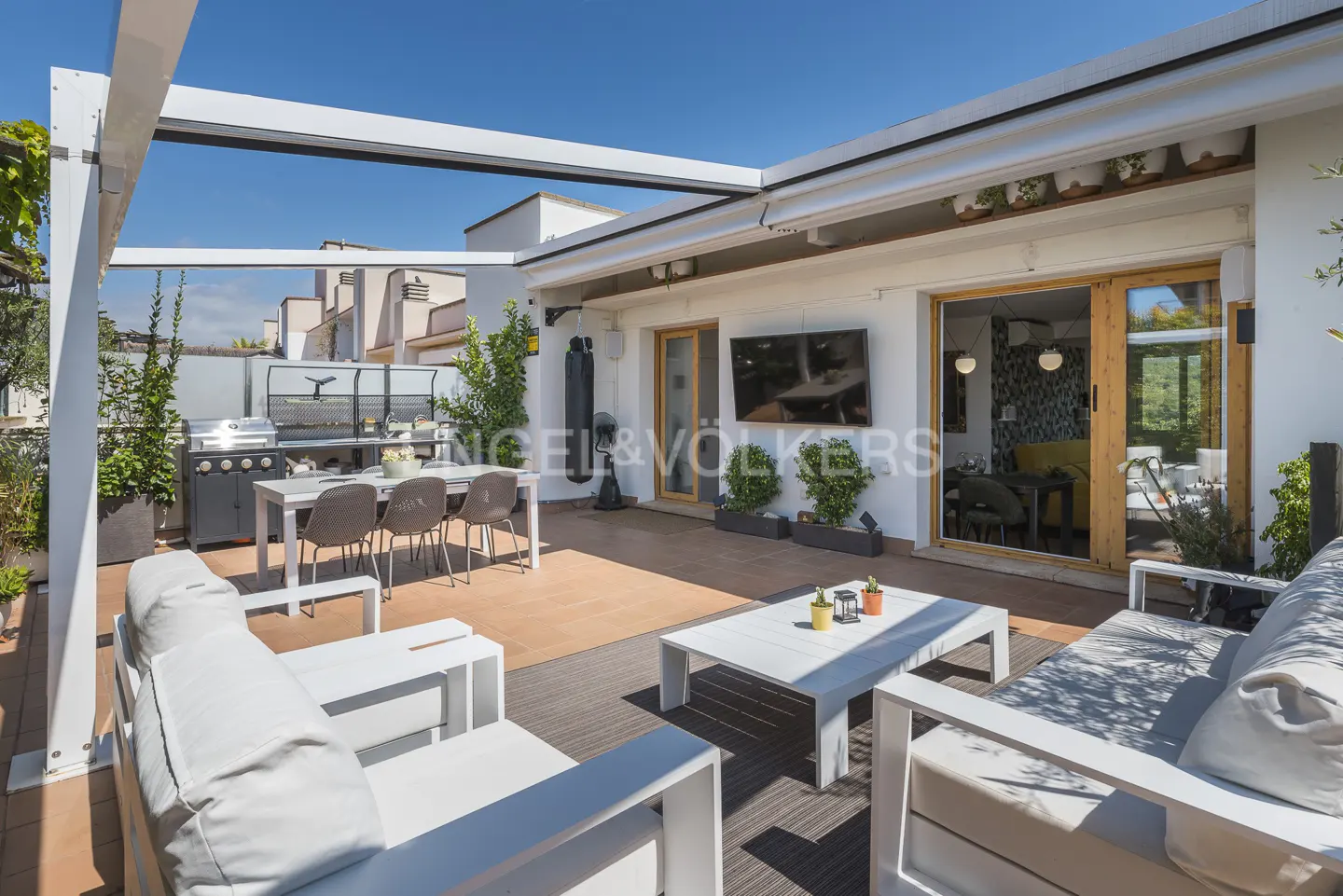 Outdoor rooftop patio with white pergola, white furniture, grill, dining table, and open sliding doors to the interior.