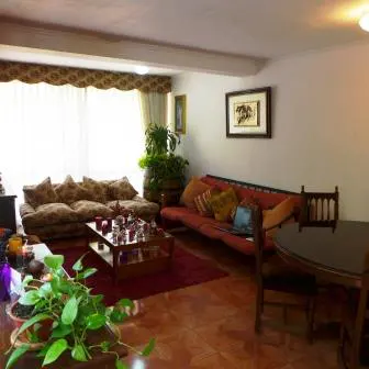 A living room with a brown sofa, a red sofa, a coffee table, and a dining table with chairs.