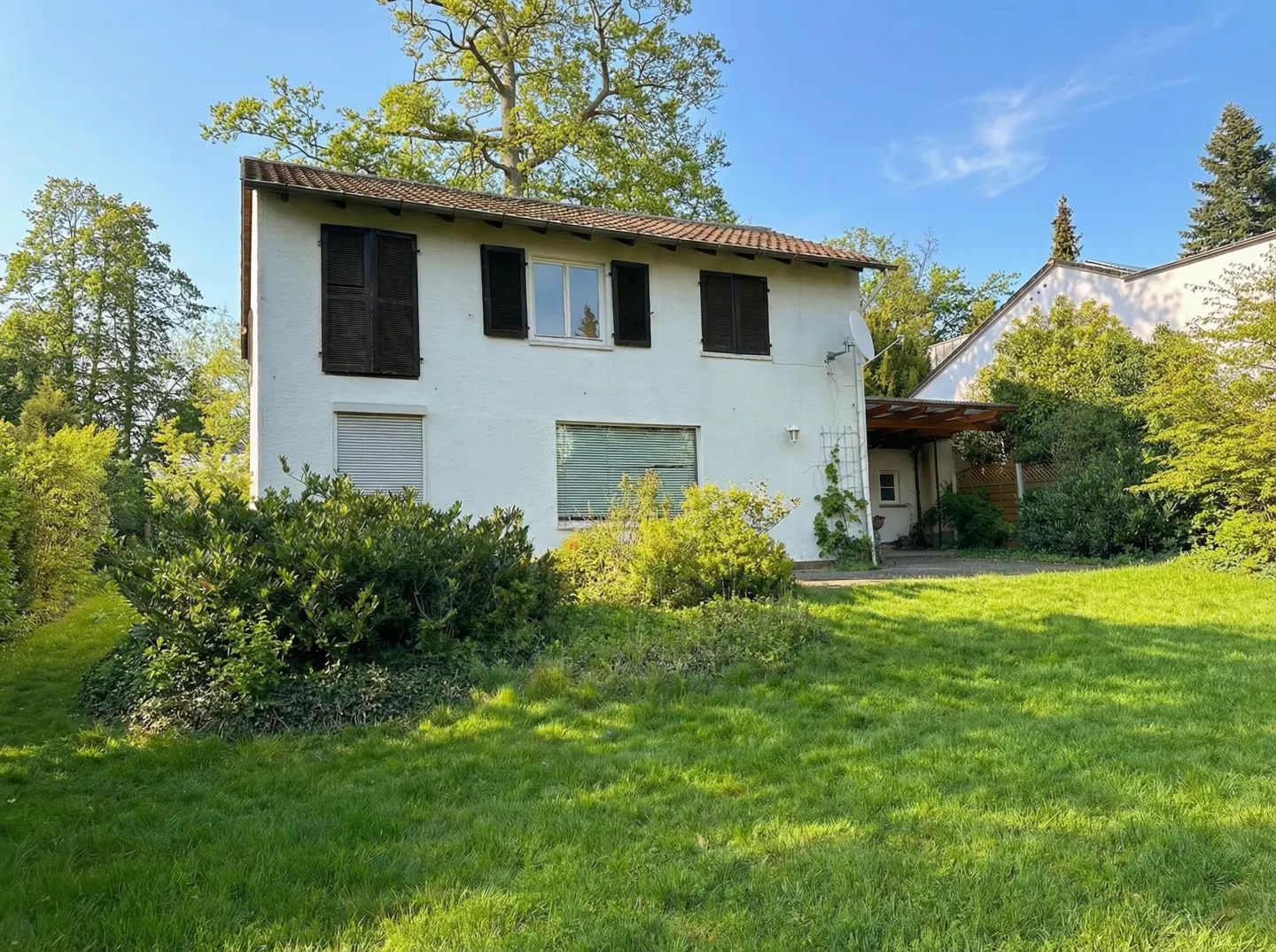 Exterior view of a two-story white house with brown shutters and a green lawn.
