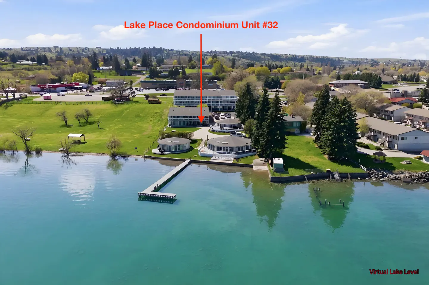 Aerial view of Lake Place Condominium Unit #32, a waterfront property with a dock on a sunny day.