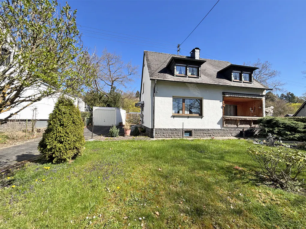 Two-story white house with a gray roof and a green lawn on a sunny day.