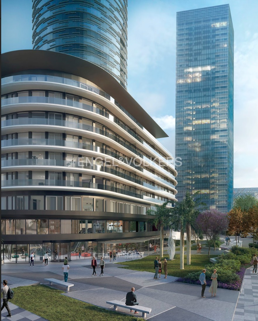 Modern architecture featuring a curved, multi-story building with glass balconies, set against a backdrop of skyscrapers and a public park with people.