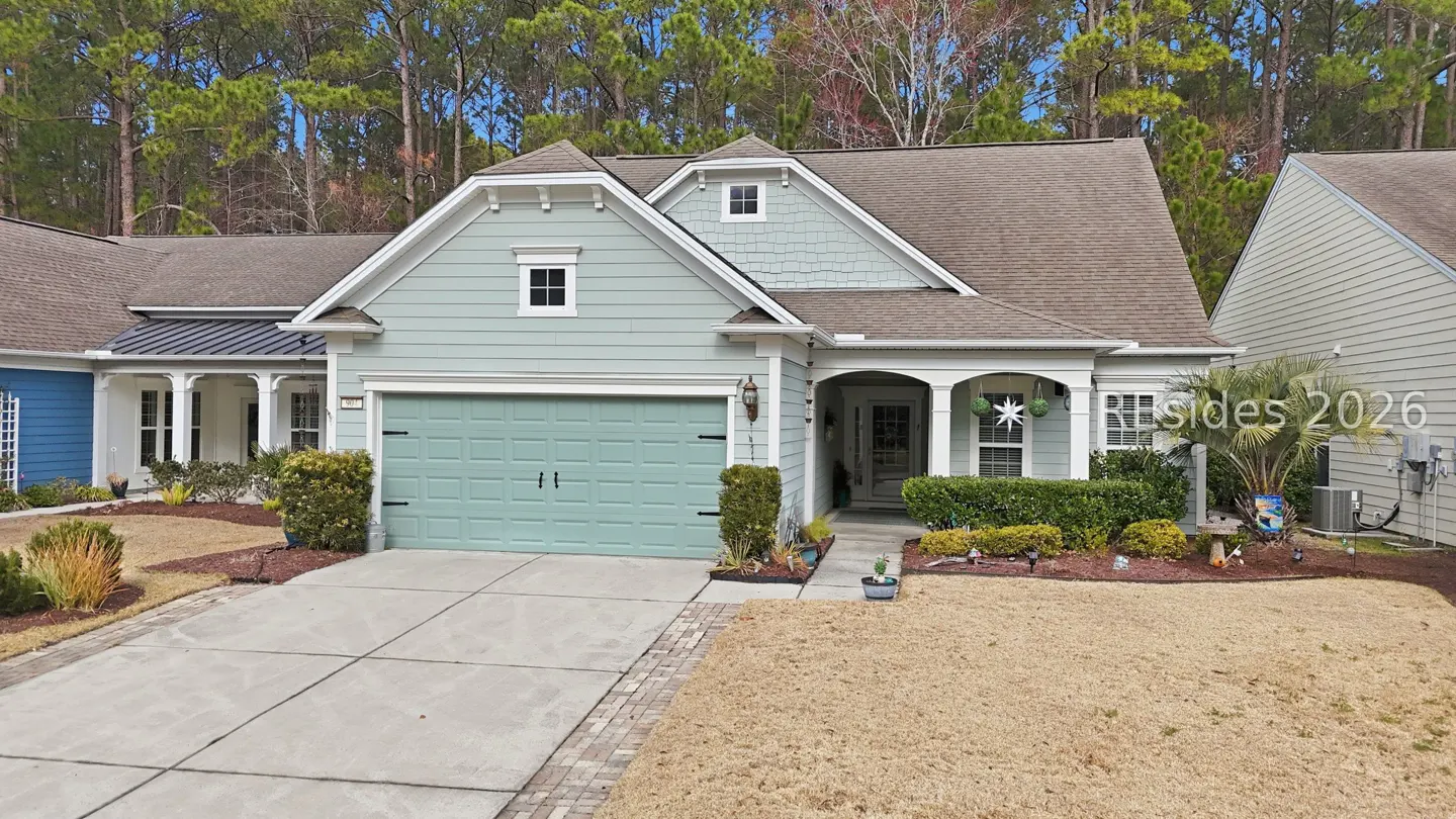 A light blue house with a matching garage door and a brown roof on a sunny day.
