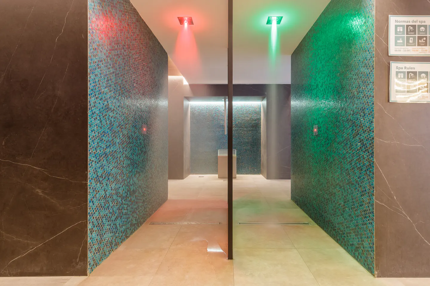 Spa hallway with mosaic tile walls, red and green lights, and a mist effect. Spa rules are posted on the right wall.