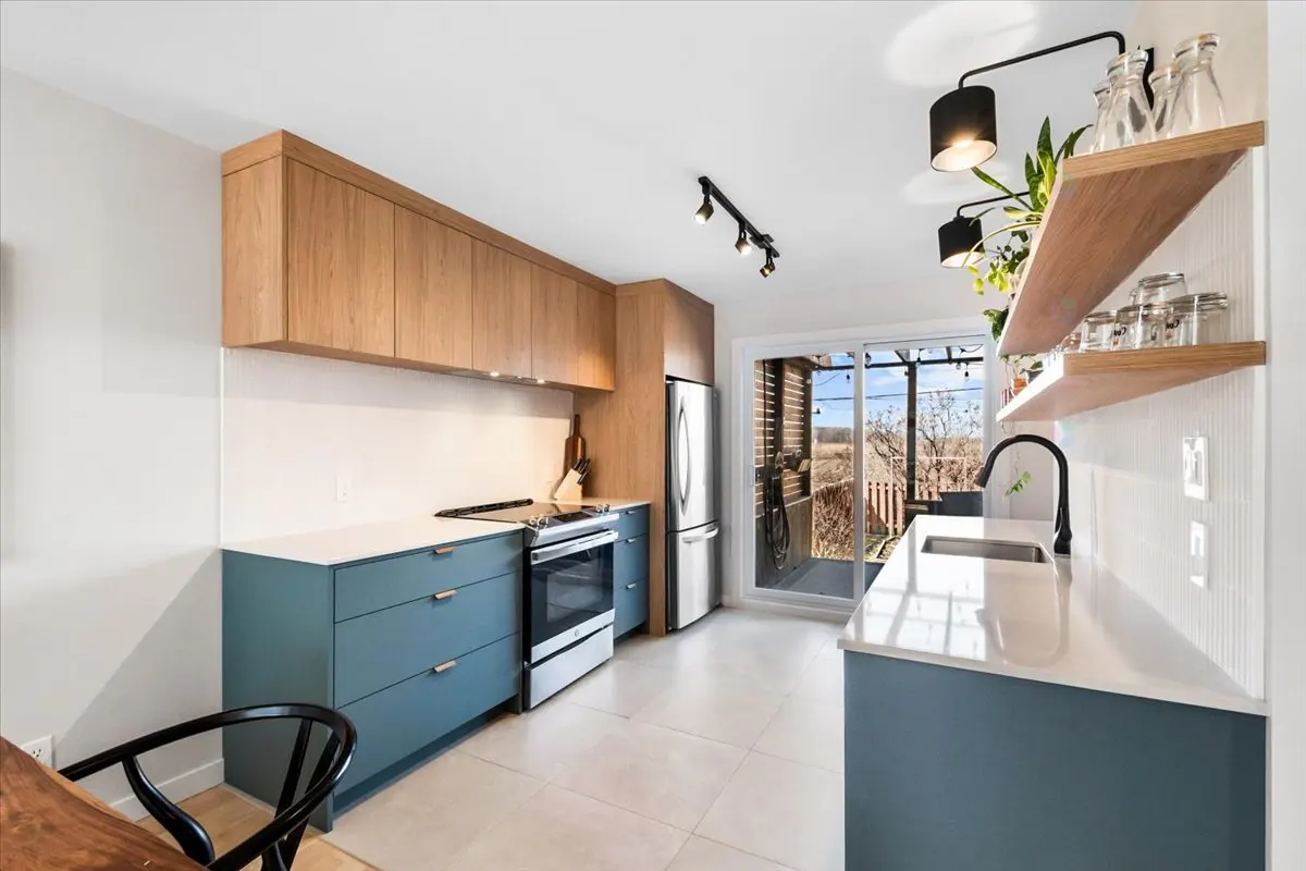 Bright kitchen with blue cabinets, wood accents, and white countertops. Sliding glass doors lead to an outdoor patio.