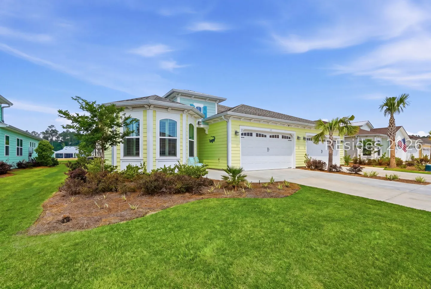 Two-story home with a two-car garage, yellow and green siding, and a well-manicured lawn.
