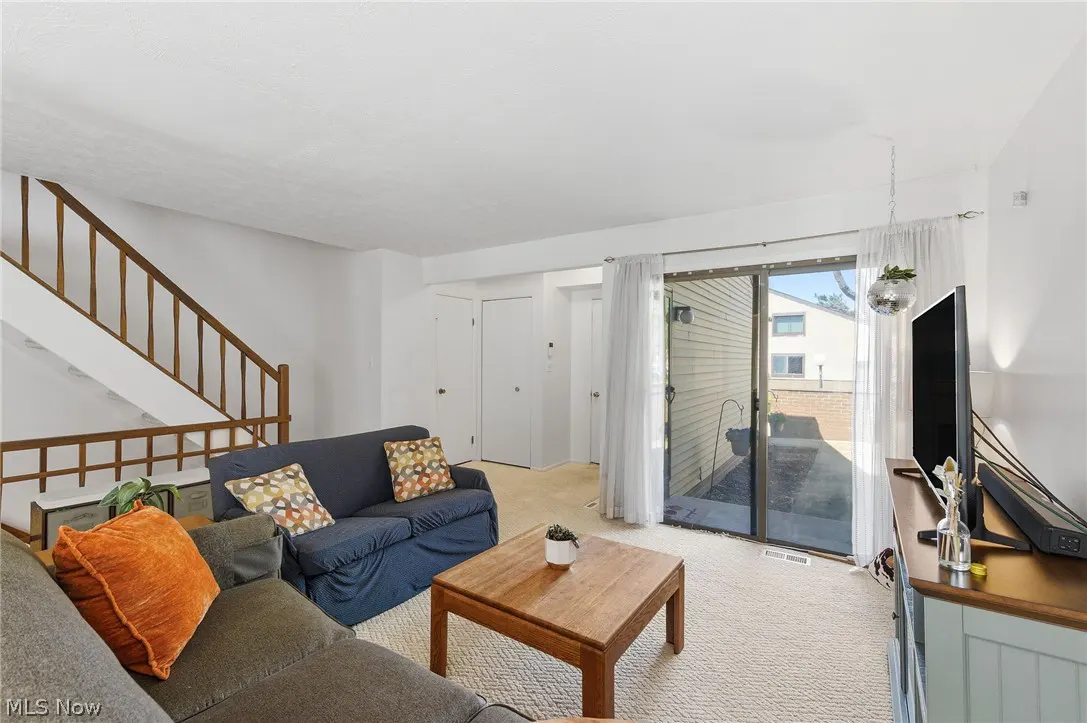Living room with a gray sectional, blue sofa, wood table, and stairs. Sliding glass doors lead to a patio.