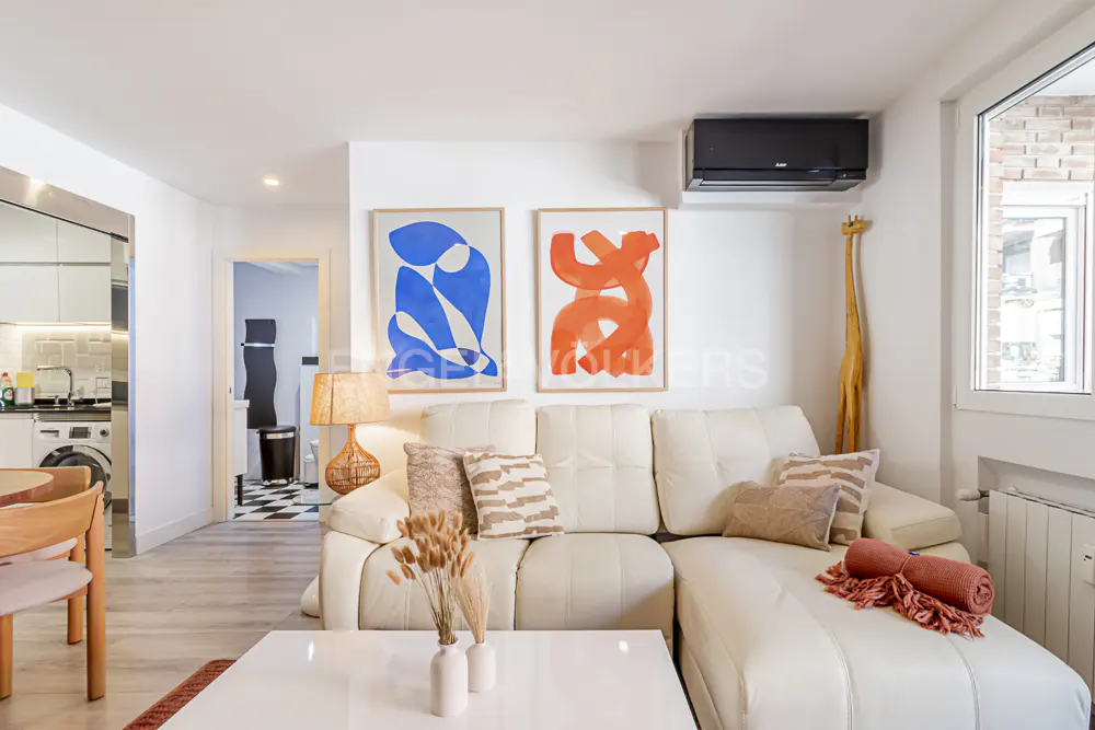Bright living room with white sectional sofa, abstract art, and a giraffe statue near a window.