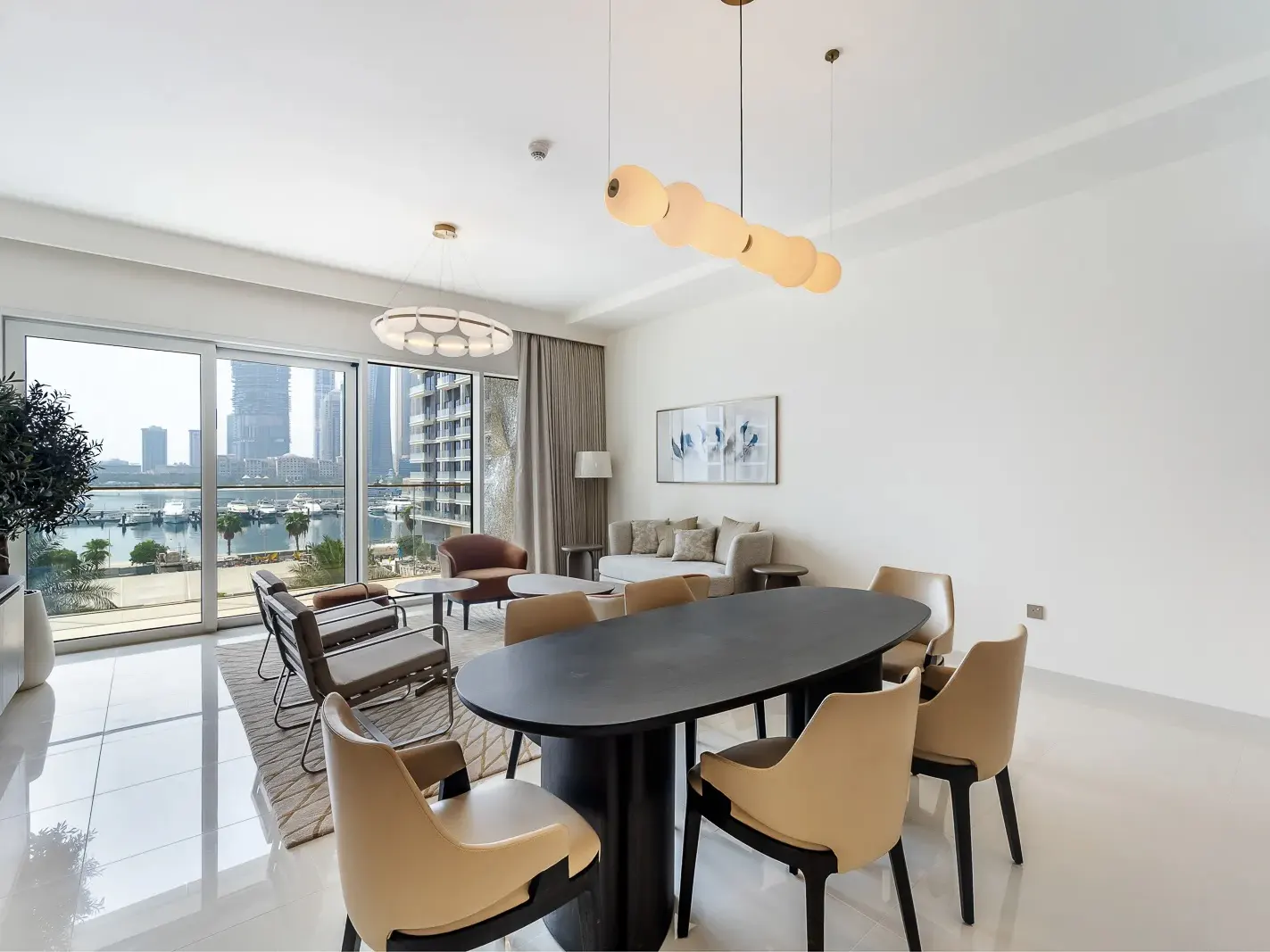 Bright, modern apartment interior with a black oval dining table, beige chairs, and a city view through large windows.