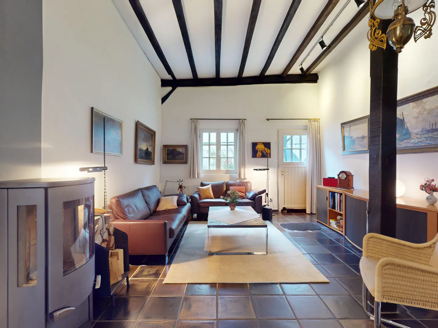 A living room with brown leather sofas, a white rug, and black ceiling beams.