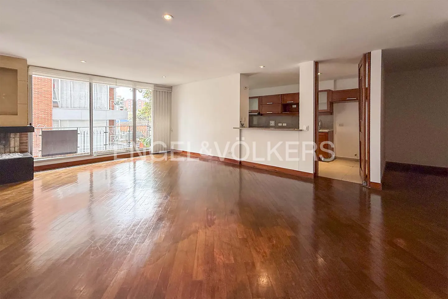 Bright, open-concept living space with hardwood floors, a fireplace, and a kitchen with wood cabinets. Balcony with city views.