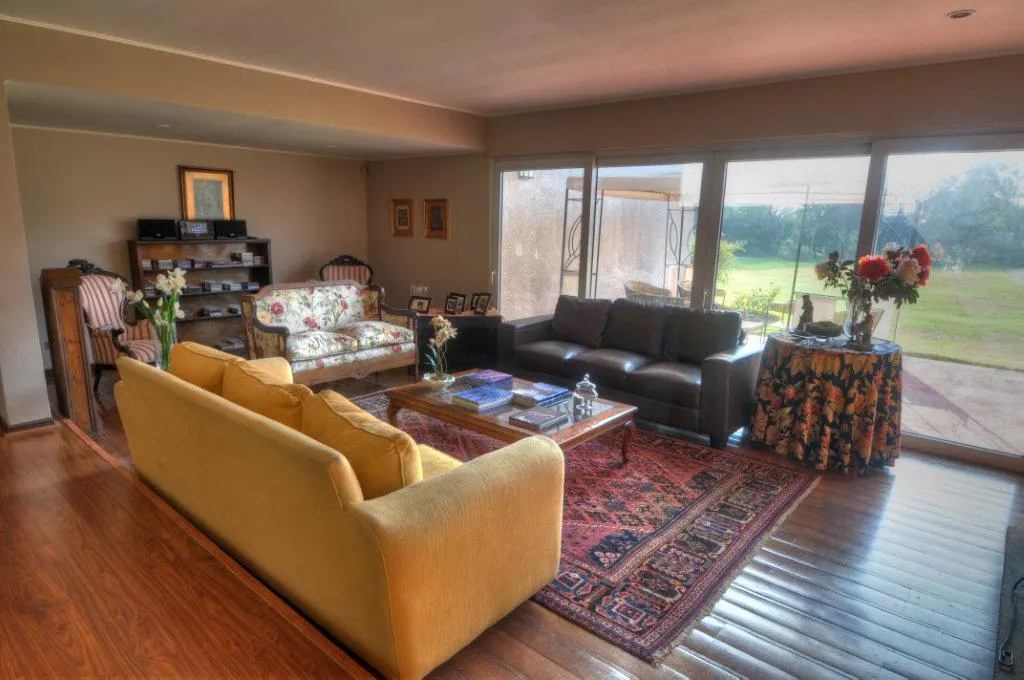 Living room with yellow sofa, brown leather couch, floral loveseat, and large windows overlooking a green lawn.