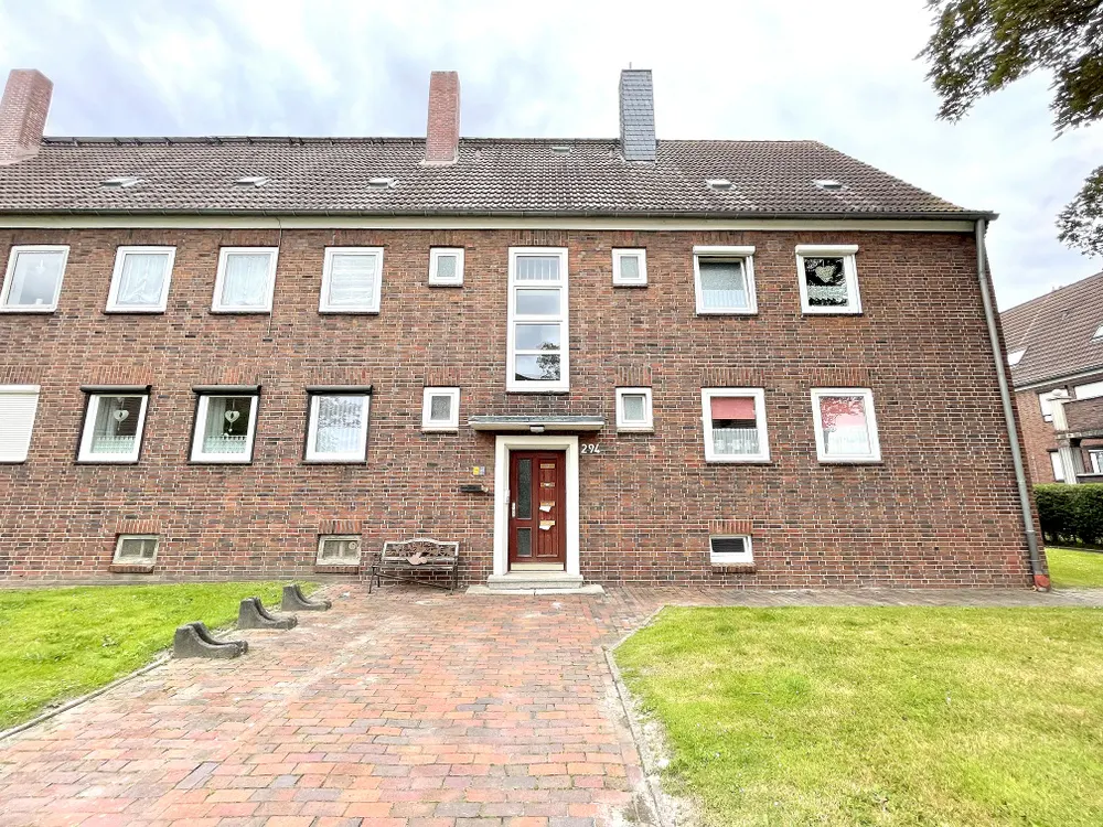 A three-story brick apartment building with a brown door and a brick walkway.
