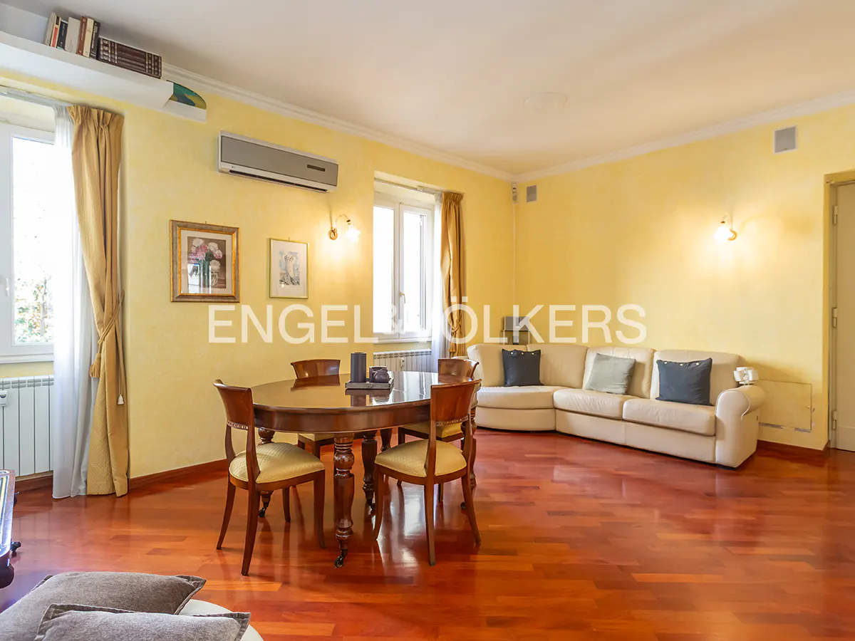 A living room with yellow walls, a wooden floor, a round table with chairs, and a beige sofa.