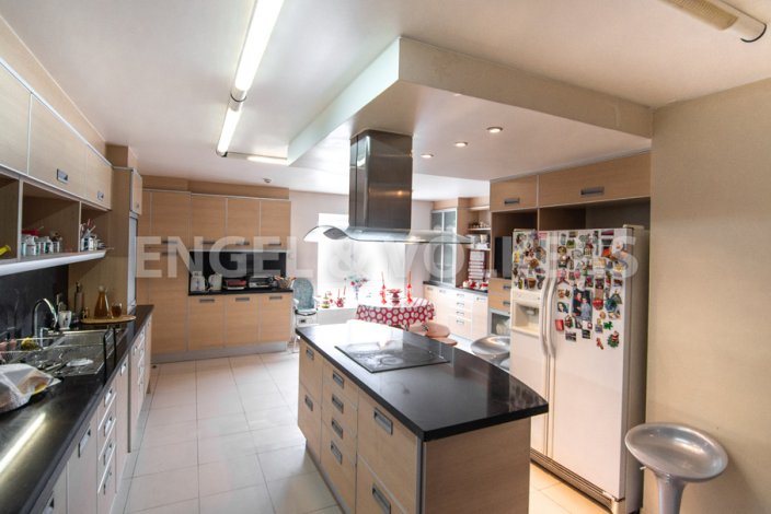 A spacious kitchen with light wood cabinets, a black countertop island, and stainless steel appliances.