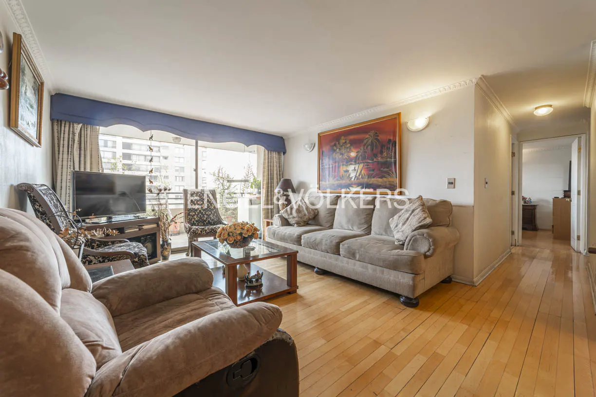 Living room with hardwood floors, brown sofas, glass coffee table, and balcony with city view. Painting on the wall.