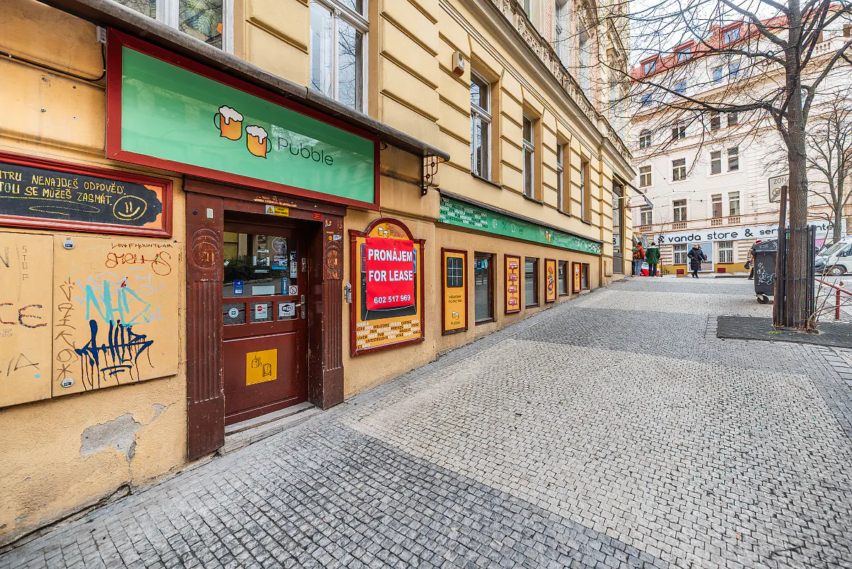 Exterior view of a building with a "Pubble" sign and a "For Lease" sign on a cobblestone street.