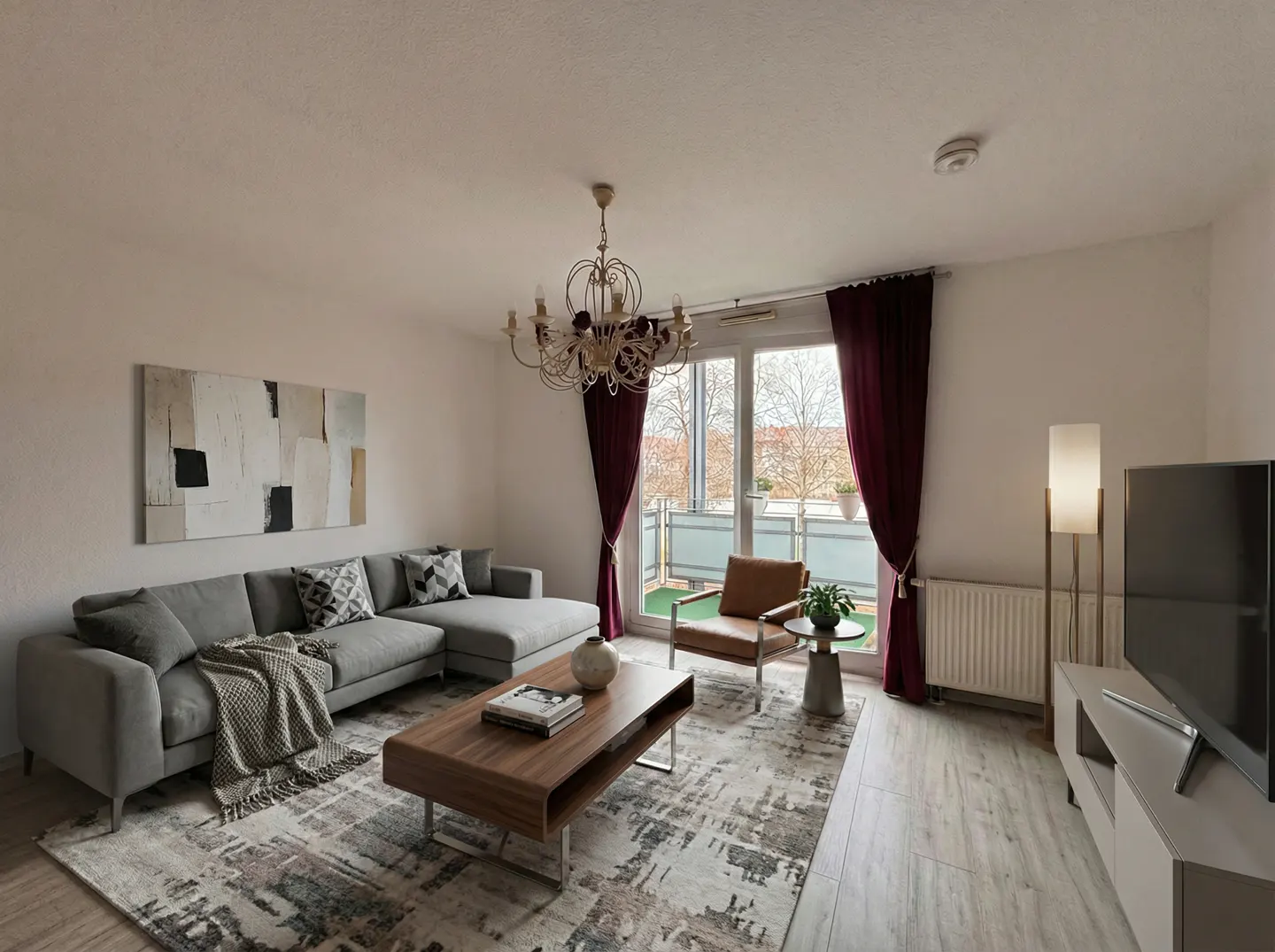 Living room with gray sectional sofa, wood coffee table, patterned rug, and balcony access with maroon curtains.