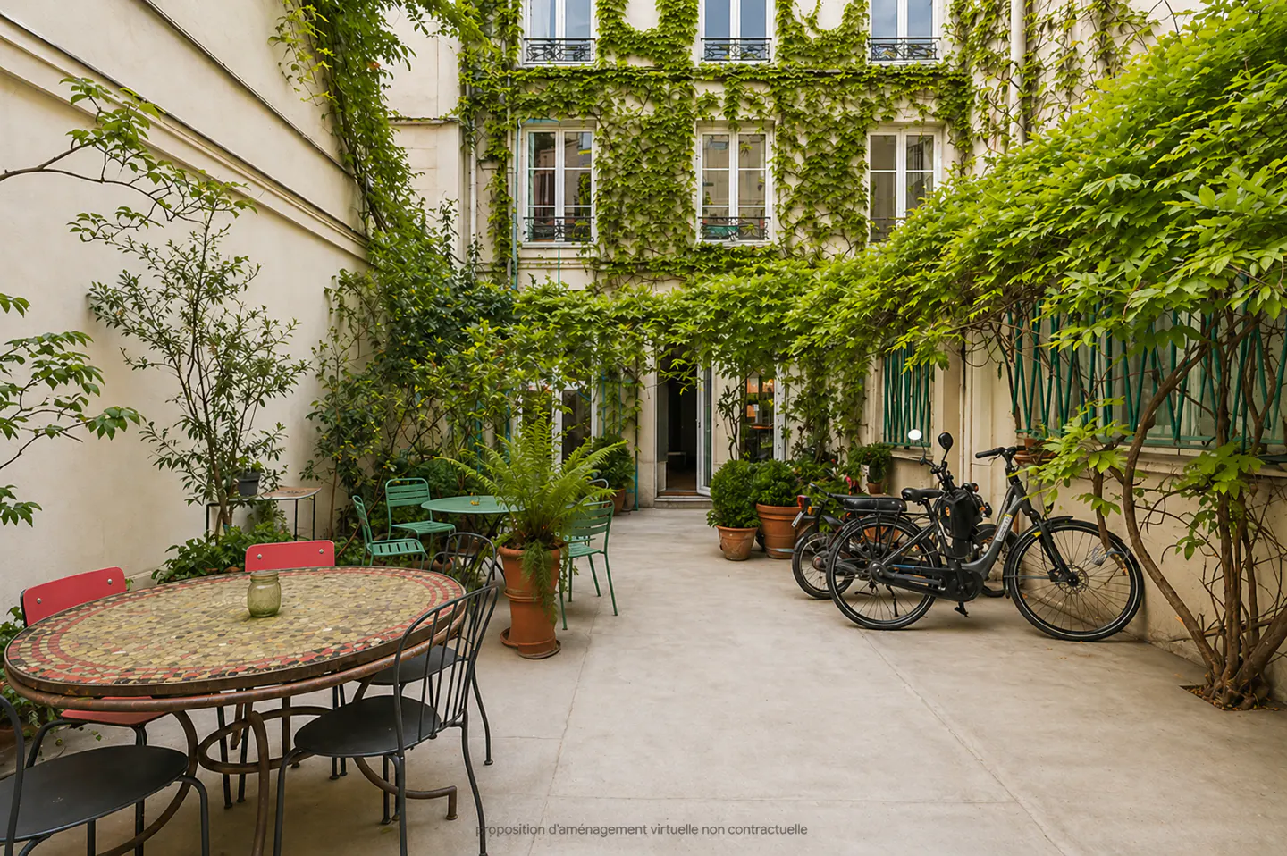A courtyard with tables, chairs, and bicycles. The building is covered in green vines.