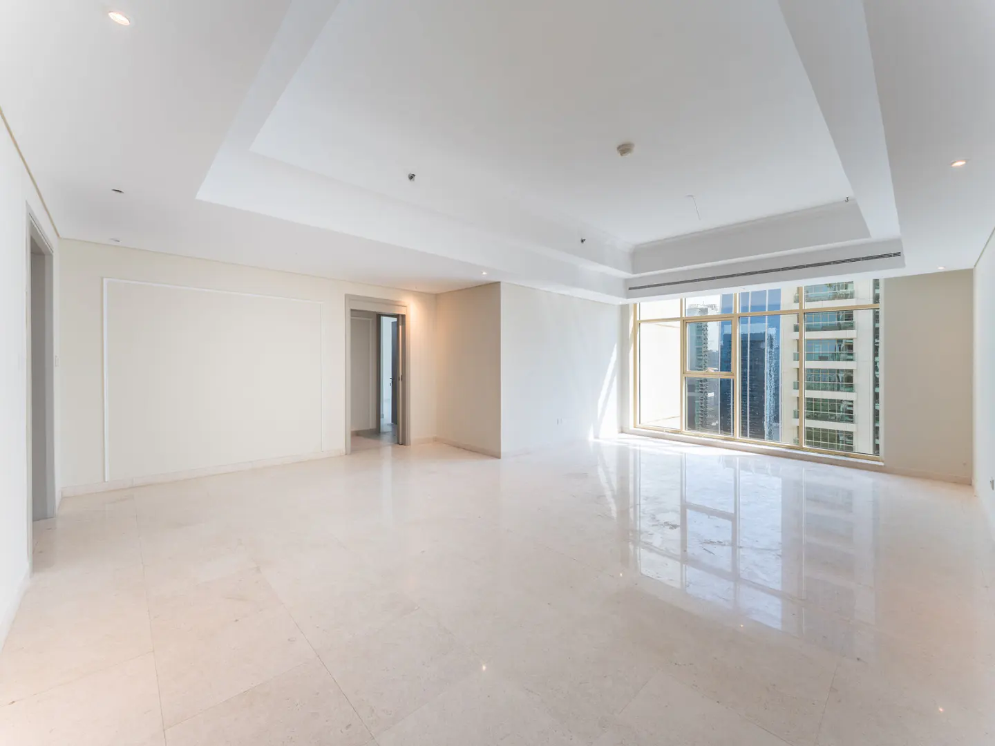 Bright, empty room with marble floors, white walls, and a large window showing a city view.