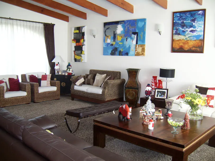 Living room with brown wicker furniture, a dark wood coffee table, and abstract art on white walls.