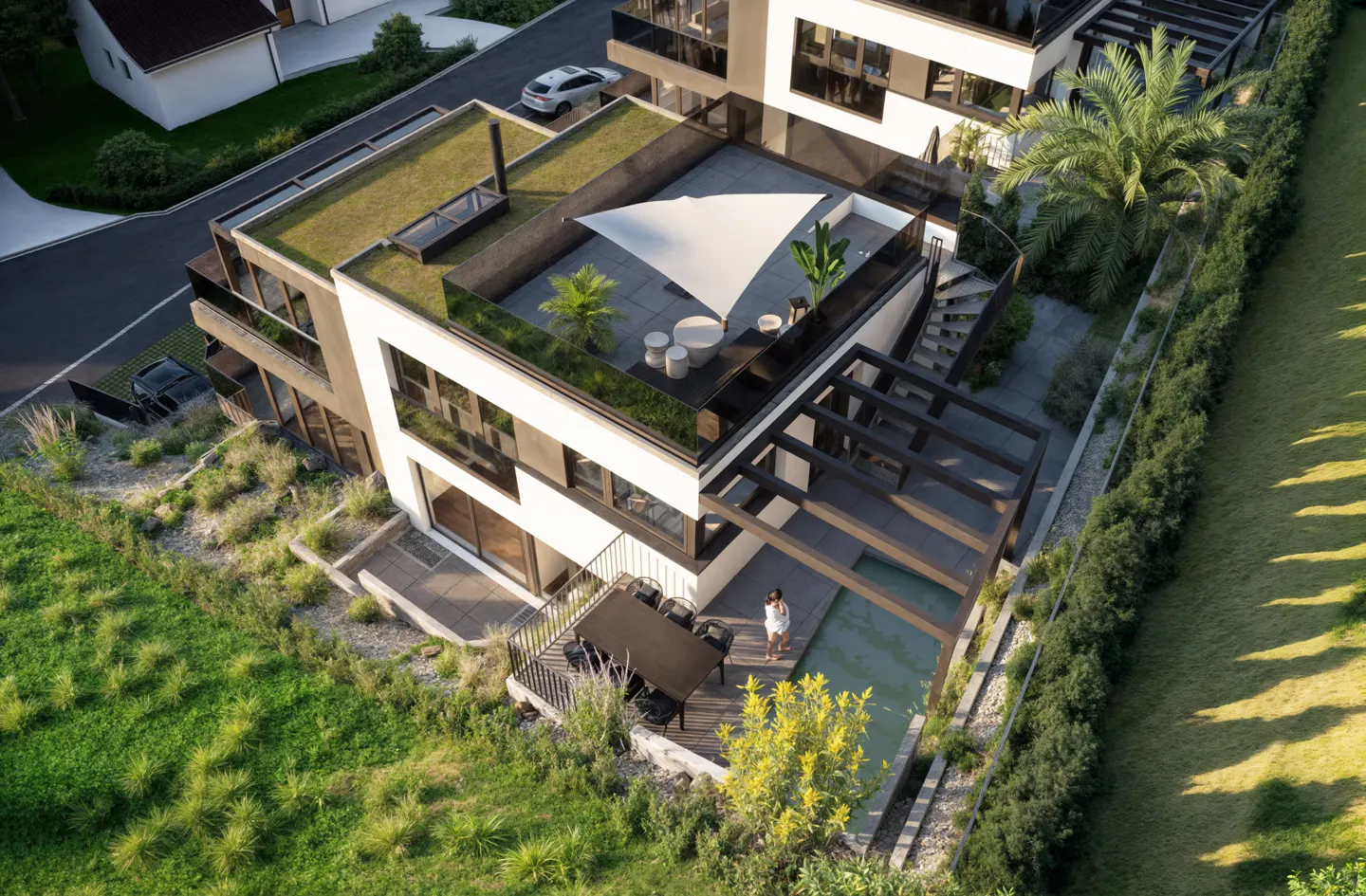 Aerial view of a modern white house with a green roof, rooftop patio, pool, and lush landscaping.