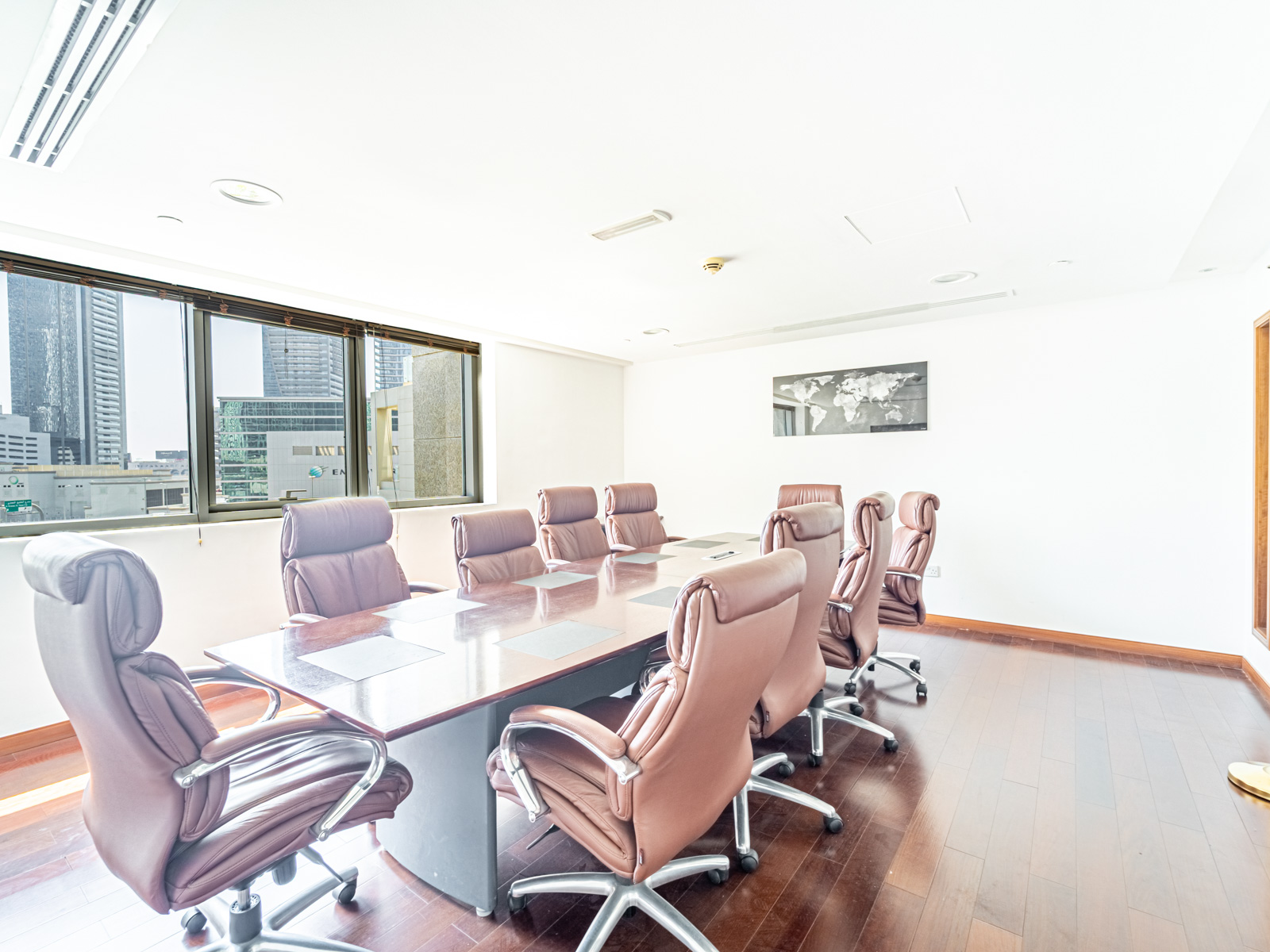 Bright office boardroom with a long wooden table, brown leather chairs, and large windows overlooking a city skyline. [AI-generated text]