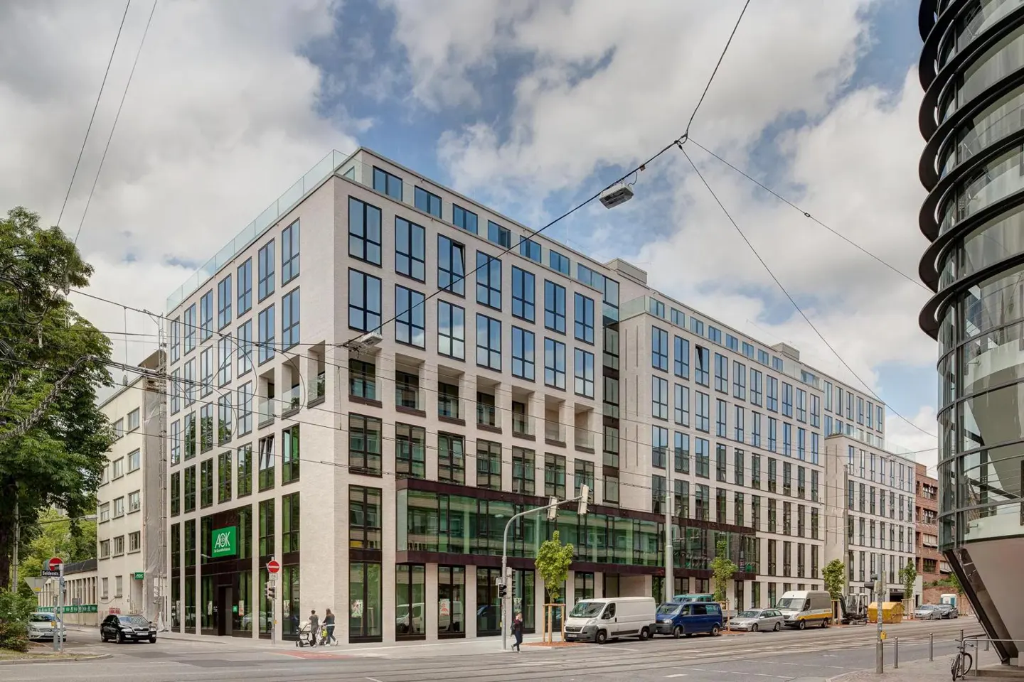 Modern white building with many windows, street view, cars and pedestrians.
