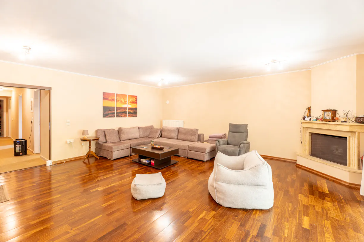Living room with hardwood floors, beige walls, a gray sectional sofa, fireplace, and two white beanbag chairs.